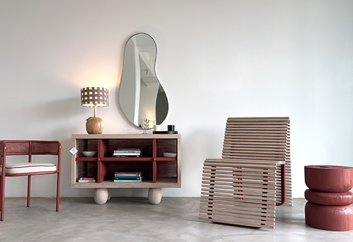 Conjunto de mobiliario moderno en interior minimalista: silla y aparador con acabados en madera, espejo orgánico y lámpara de mesa, con acento en tonos tierra.